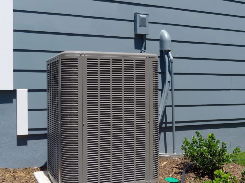 Air conditioner installed outside of a grey/blue sided home